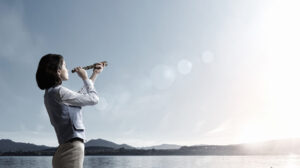 Young businesswoman looking in spyglass on sunrise at horizon